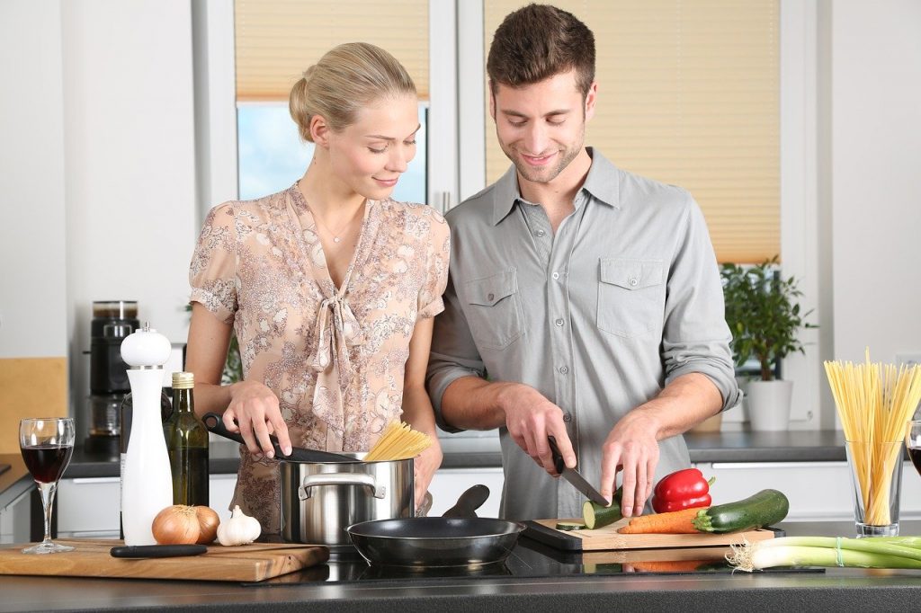 Young couple cutting up food and cooking together.